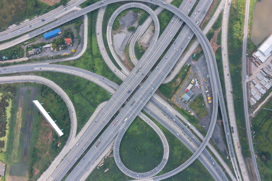 Aerial view of highway junctions with roundabout. Bridge roads shape circle in structure of architecture and transportation concept. Top view. Urban city, Bangkok at sunset, Thailand