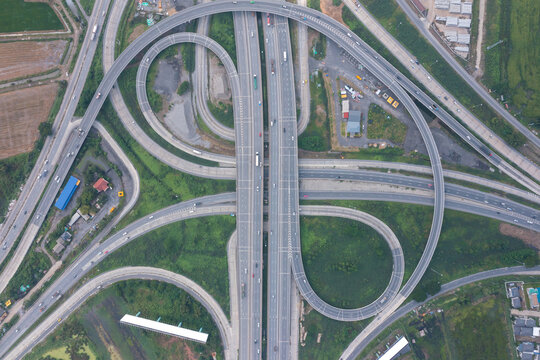 Aerial view of highway junctions with roundabout. Bridge roads shape circle in structure of architecture and transportation concept. Top view. Urban city, Bangkok at sunset, Thailand
