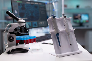 Nobody in research laboratory with micro pipette on desk. Empty scientific development room with professional equipment, microscope and lab glassware. Biochemistry cabinet with tools