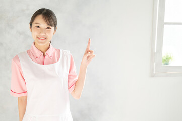 Image of Asian (Japanese) woman pointing at something for childcare, kindergarten, and nursing jobs.