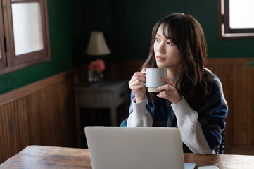 コーヒーを飲みながらくつろぐアジア人（日本人）女性　コピースペースあり	