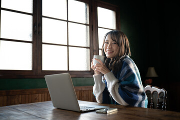 コーヒーを飲みながらくつろぐアジア人（日本人）女性　カメラ目線　コピースペースあり　広角