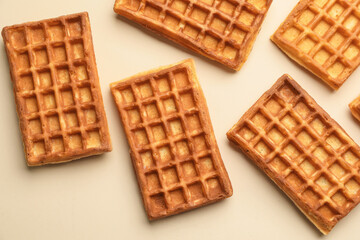 Tasty golden Belgian waffles on beige background