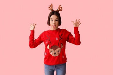 Grimacing young woman in stylish Christmas clothes on color background