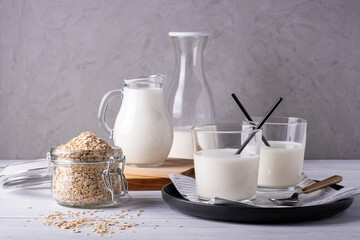 Composition of various glass serving vessels with oat milk and oatmeal containers. Alternative to lactose-free milk. Healthy and dietary food. Selective focus.