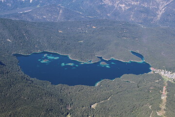 mountain lake with clear blue water surrounded by trees from above 