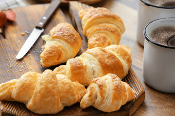 Board with fresh croissants on table