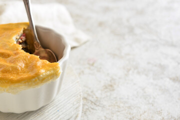 Wooden board with tasty vegetable pot pie on light background, closeup