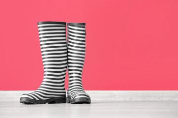 Rubber rain boots on floor near color wall