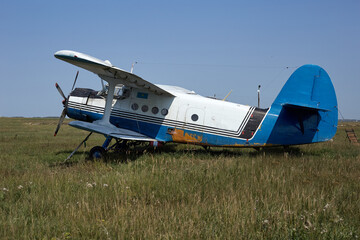 The old plane is at the airfield in a green field in good condition can fly