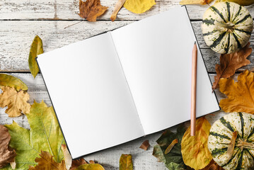 Beautiful autumn composition with book and leaves on white wooden background
