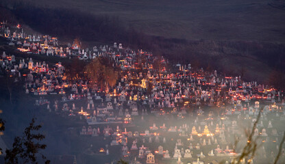 Obraz premium Candle lights on graves in cemetery at night on All Saints’ Day or All Souls’ Day or Halloween