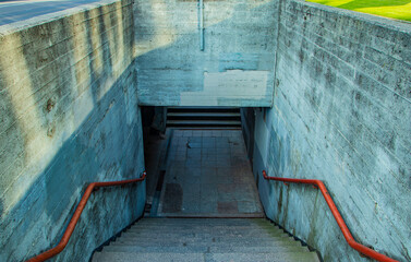 Urban background of the entrance and stairs of an old concrete pedestrian subway tunnel with red...