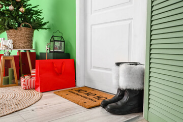 Santa boots near door in room decorated for Christmas