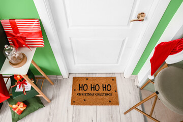 Door mat with Christmas greeting and gifts in room