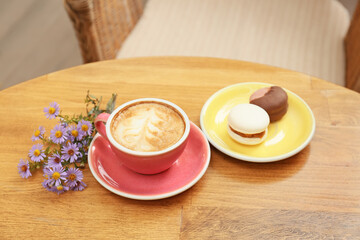 Cup of tasty coffee, asters flowers and dessert on table in cafe