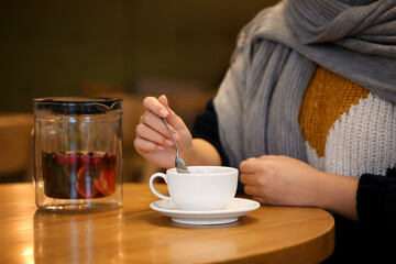 Young woman drinking tea at table in cafe, closeup