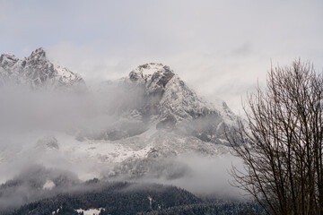 Obraz premium Wilder Kaiser in Tirol Österreich mit ersten Schnee im Jahr umhüllt von Wolken und Nebelschwaden.