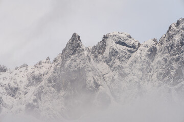 Fototapeta na wymiar Wilder Kaiser in Tirol Österreich mit ersten Schnee im Jahr umhüllt von Wolken und Nebelschwaden.