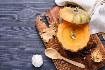 Tasty soup served in pumpkin on black wooden background