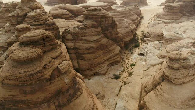 Aerial Descending Into Stunning Rock Formations In The Saudi Arabian Desert With Bright Sunlight And Stark Surroundings