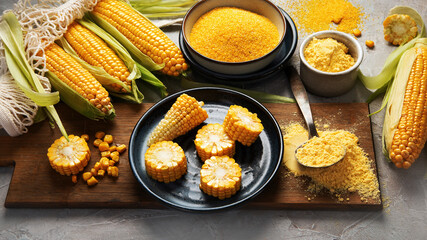 Corncobs and corn groats on gray background.