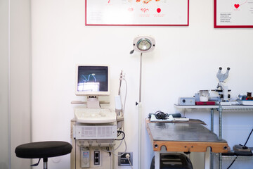 Veterinary clinic with an examination table, workstation, and cabinets filled with medical supplies.