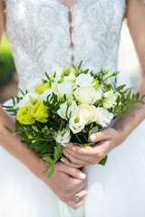 Obraz na płótnie Canvas Bride holds in hands beautiful floral wedding bouquet made with white and yellow roses