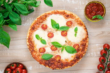 Close-up Margherita pizza on light wooden table. Traditional italian food: delicious pizza with mozzarella, basil and cherry tomatoes