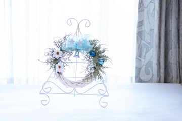 リース台に飾った星模様の青いリボンと白のポインセチアのクリスマスリース（窓辺）