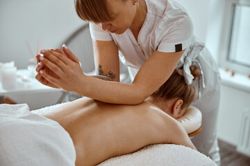 Obraz na płótnie Canvas Professional confident massage master is doing procedures to caucasian woman in minimalistic modern cabinet