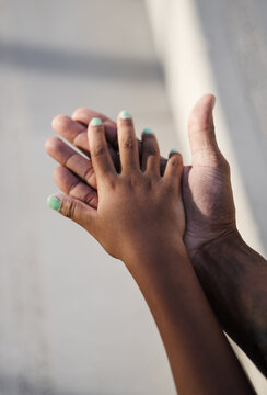 Vertical shoot of two hands touching one each other of dominican father and daughter