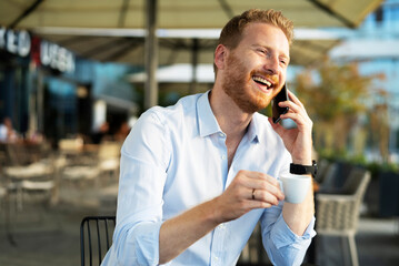 Handsome businessman drinking coffee in cafe. Young man talking to the phone
