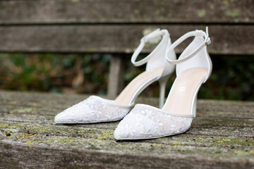 White wedding shoes with lace and heel on old wooden boards