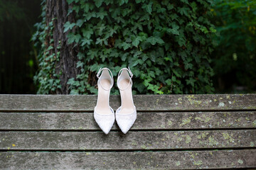White wedding shoes with lace and heel on old wooden boards