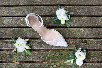 White wedding shoe with white flowers on old wooden boards