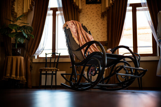 antique armchair with a plaid in the office against the background of the windows of an old house