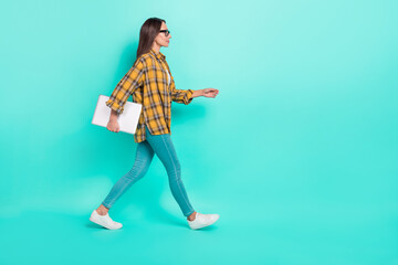 Full body profile photo of ceo mature brunette lady go with laptop wear eyesight shirt jeans sneakers isolated on teal background