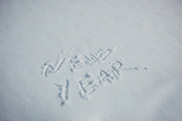 Drawing in the snow, words written by a human hand. New Year's concept.