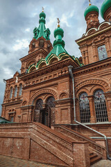 Fototapeta na wymiar Orthodox Russian temple with green domes against the backdrop of a cloudy gloomy sky