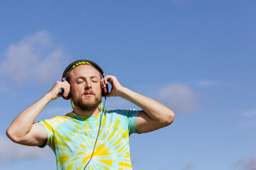 A man with an interesting mohawk hairstyle stands on the bridge and puts on headphones