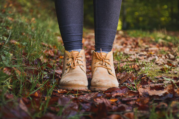 close up view of a woman legs wearing mountain boots, autumn leaves background