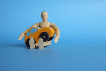 Car insurance and protection concept. Wooden human figure hug toy car on blue background. Copy space for text.
