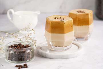 Two glasses with trendy korean beverage dalgona coffee latte - whipped instant coffee, sugar and...