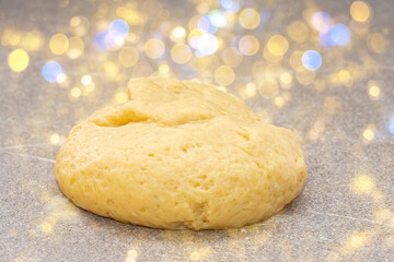 Fresh yellow raw dough in the shape of a ball for baking gingerbread men for Christmas on a fabulous background