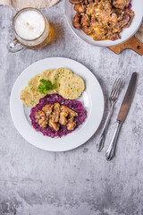 Typical Czech national meal with homemade bread dumplings red cabbage and beer on stone background. Roast pork with dumplings and sauerkraut. Top view. Vertical photo.