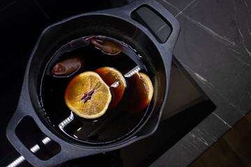 mulled wine with oranges in the pot on the cooker in cold colors