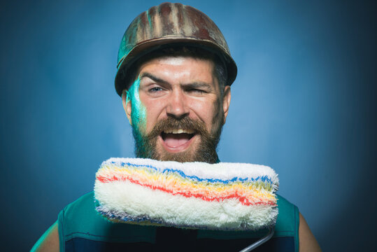 Professional painter. Man in industrial concept. Confident smiling painter and decorator posing with paint roller. Designer, builder, worker concept - bearded foreman in uniform holds paint roller.