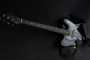 Obraz premium Background. Electric guitar through paper. Music instrument. Black electro-guitar.