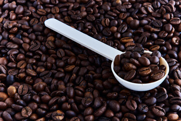 Coffee beans and a plastic spoon scattered on the table.